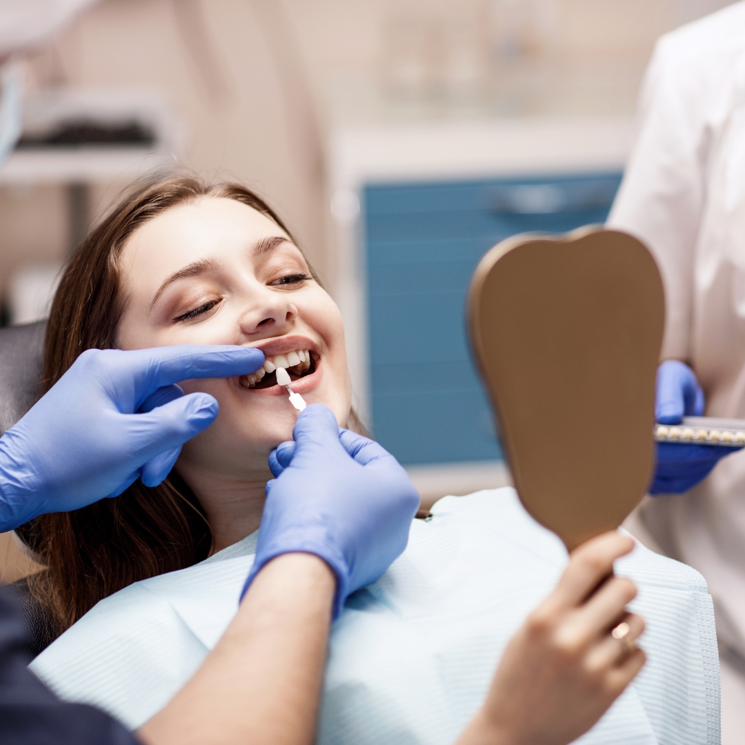 A woman in a dentist's chair smiling while having a consultation for cosmetic dental services.