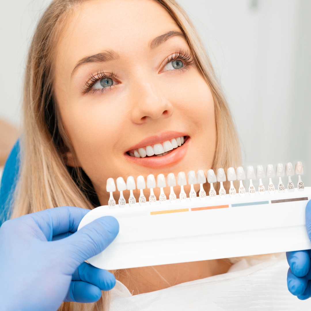 A smiling woman with a set of veneers while having a cosmetic dentistry consultation.
