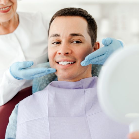 A smiling man having a prosthodontics Full Mouth Reconstruction consultation.
